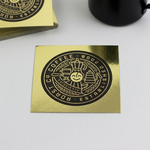 gold foil stickers with black logo and text on a white surface