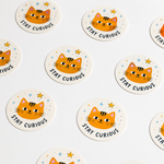Multiple 1 inch round stickers with a "Stay Curious" orange cat design laid out in a repeating pattern, showcasing bulk custom sticker logo printing.