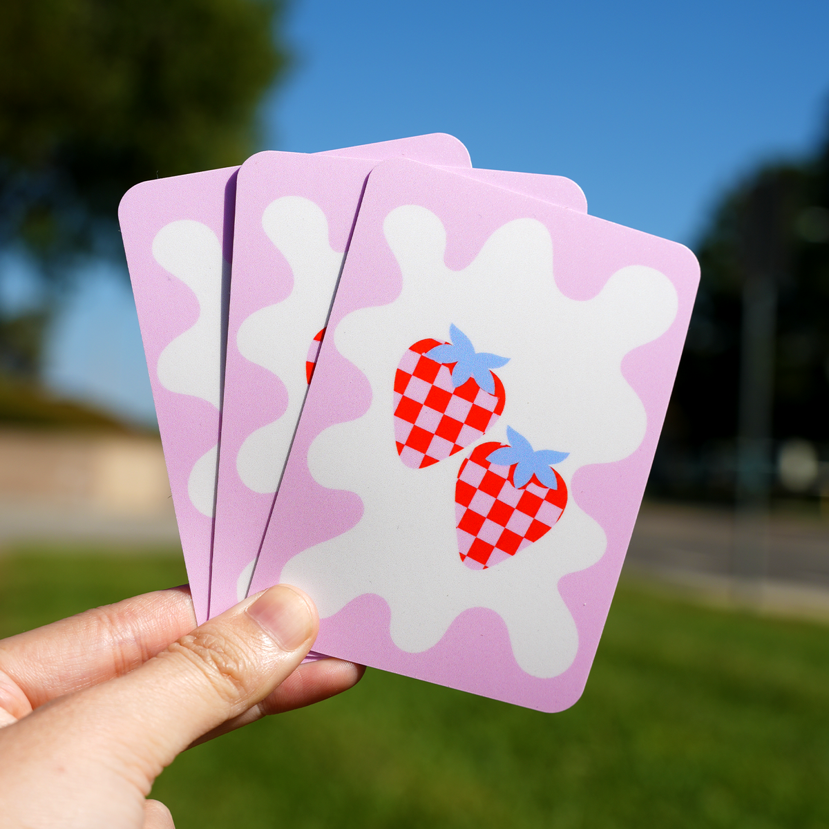 Rounded corner square stickers with a cute checkered strawberry design on a pink and white background, showcasing custom rounded corner stickers