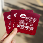 A hand displaying dark red rounded rectangle stickers with a potato chips cartoon branding design, perfect for rounded corner rectangle stickers