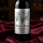 An elegant brushed silver foil wine label with detailed grape illustrations and "Vintner’s Reserve" typography on a dark glass bottle.