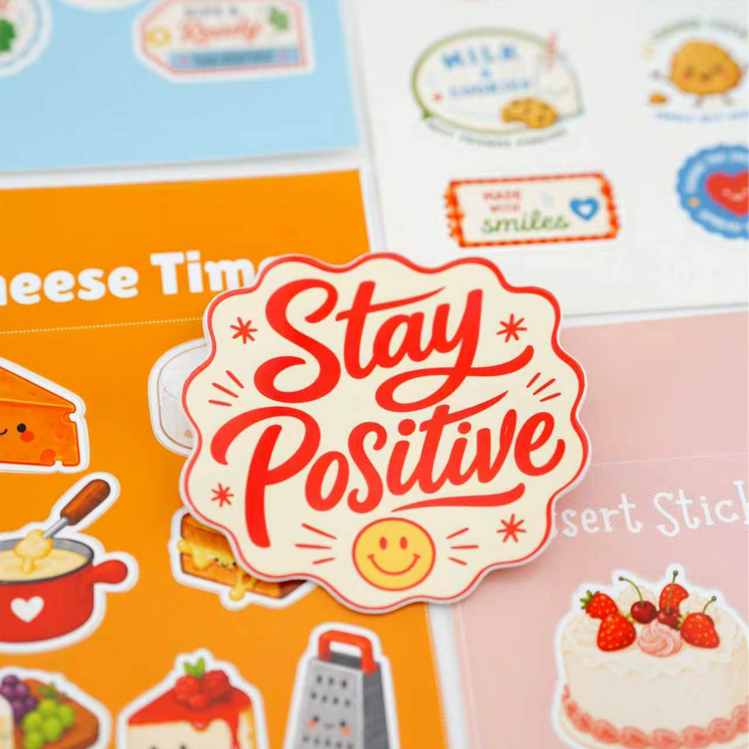 Stay Positive die-cut vinyl sticker with red typography and a smiley face surrounded by various cute designs.