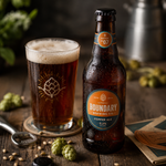 A chilled brown beer bottle covered in condensation droplets showcases a custom waterproof vinyl label for Boundary Brewing Co's Copper Ale, set on a rustic wooden table next to a poured glass of craft beer, fresh hops, and an opener.