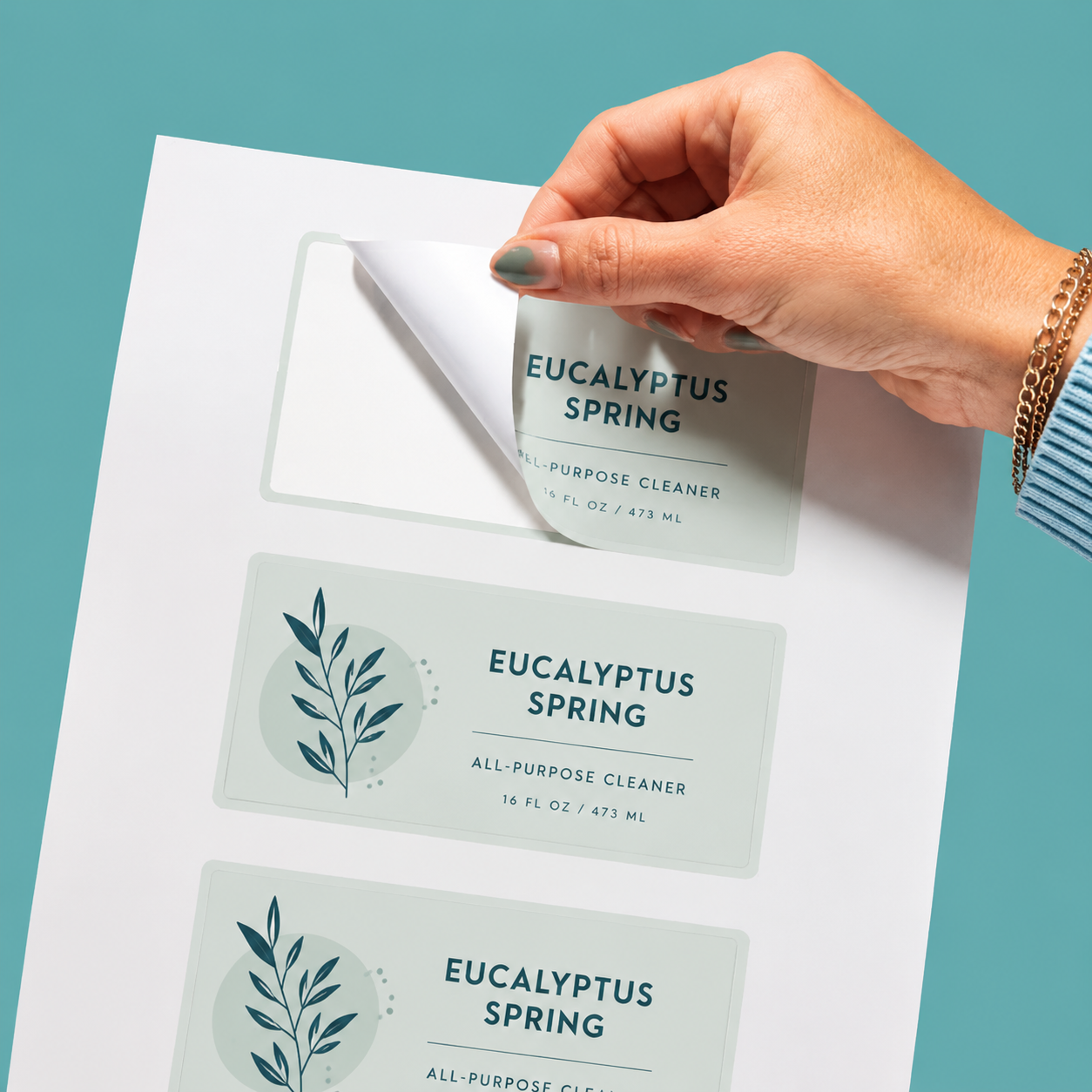 A hand peeling a weatherproof vinyl label for Eucalyptus Spring all-purpose cleaner from a sticker sheet.