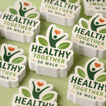 Stacks of green and white custom health event stickers prepared for wholesale orders.