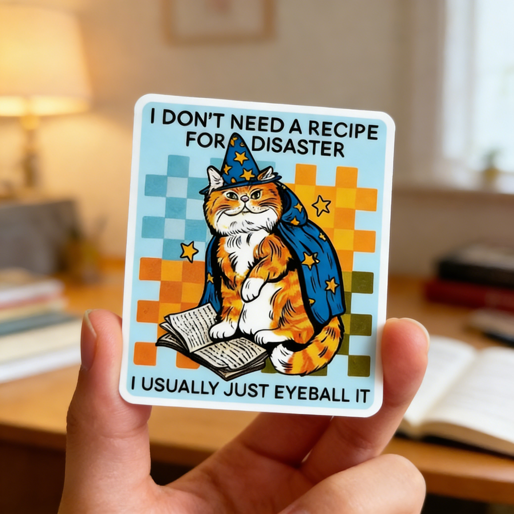 Card with a cat in a wizard hat and text held by a hand in an indoor setting.